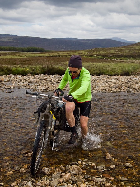 Image of Reuben hopping across the Geldie Burn (in the Cairngorms) to keep one foot dry!